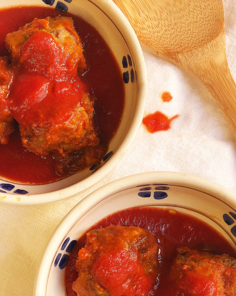 meatball with tomato sauce on 2 little pans with a wooden spoon
