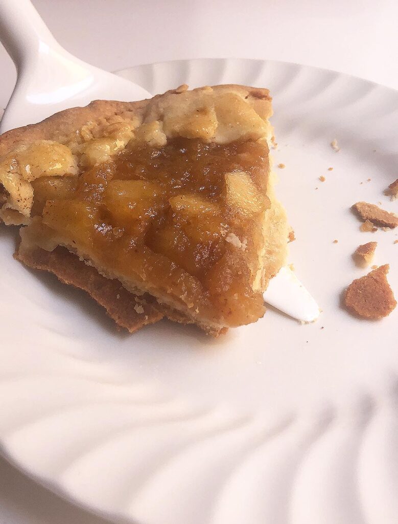 a slice of "crostata" cake with caramelized apples on a white dish