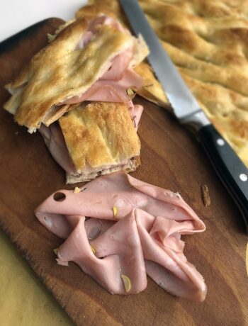 slices of mortadella salami and pizza on a chop board