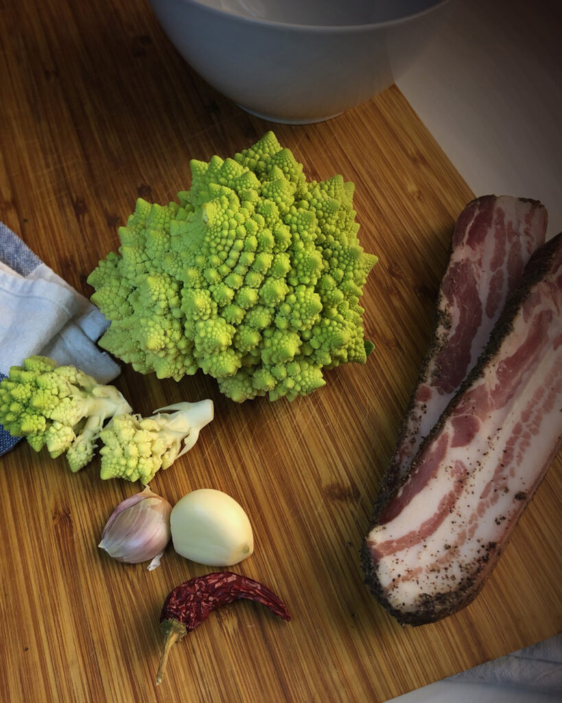 broccolo, pancetta, garlic and chili pepper on a chop board