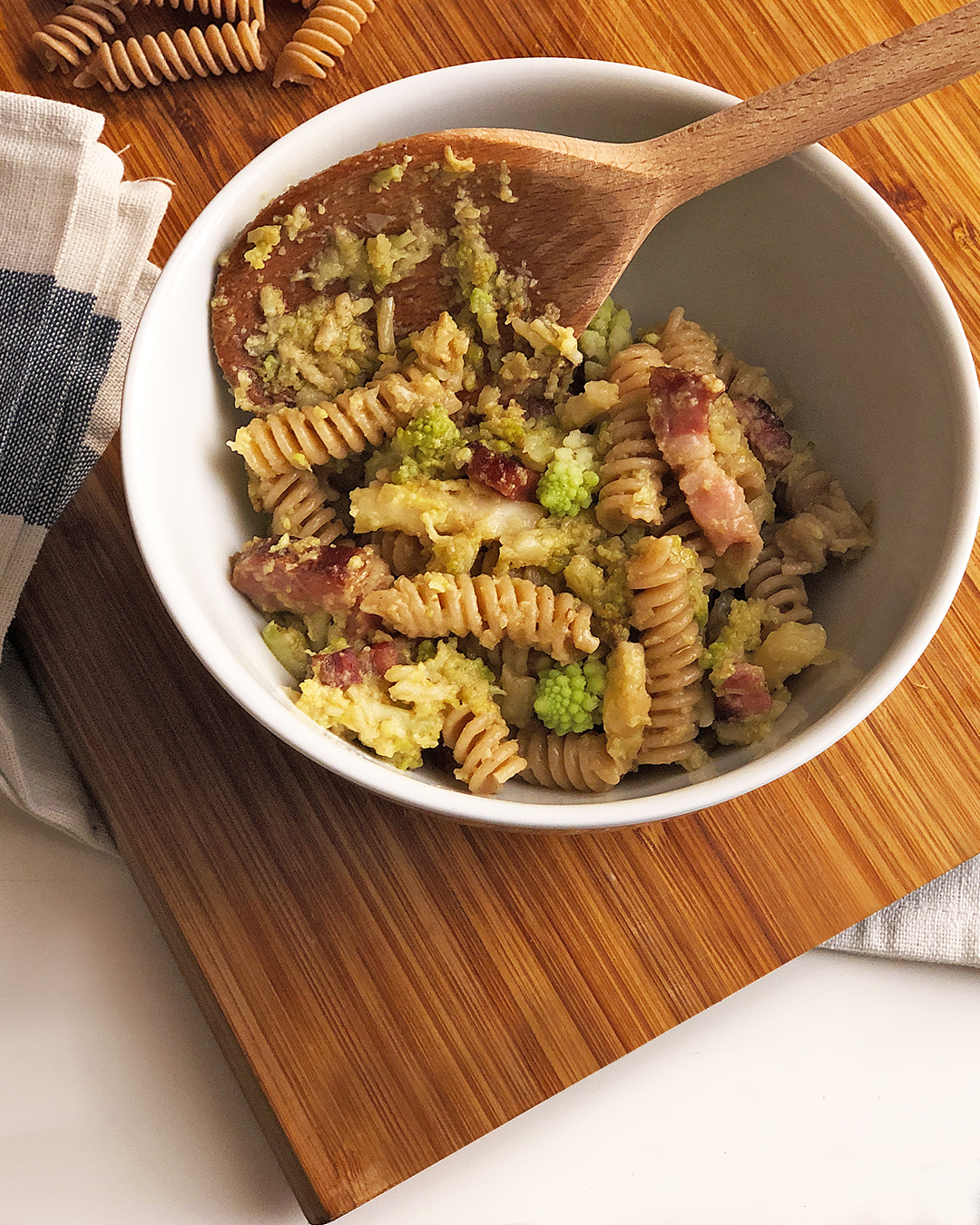 pasta with broccoli into a pan on a chop board