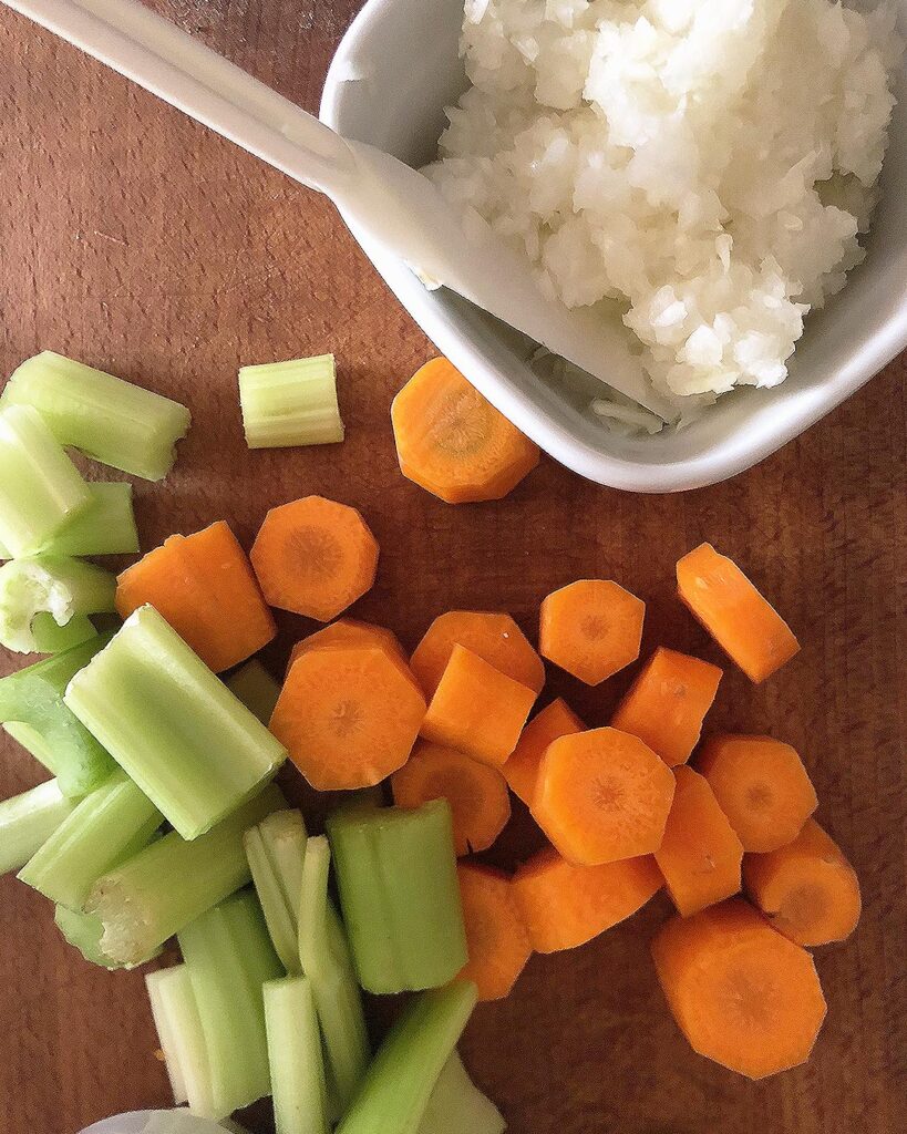 chopped onions, carrots and celery on a chop board