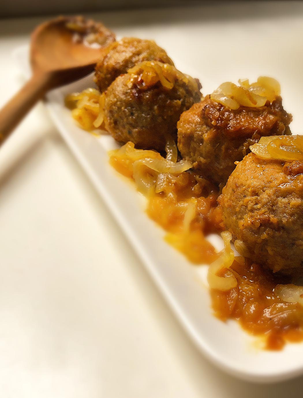 Polpette "My Way". Meatballs on a dish with a wood spoon on the background