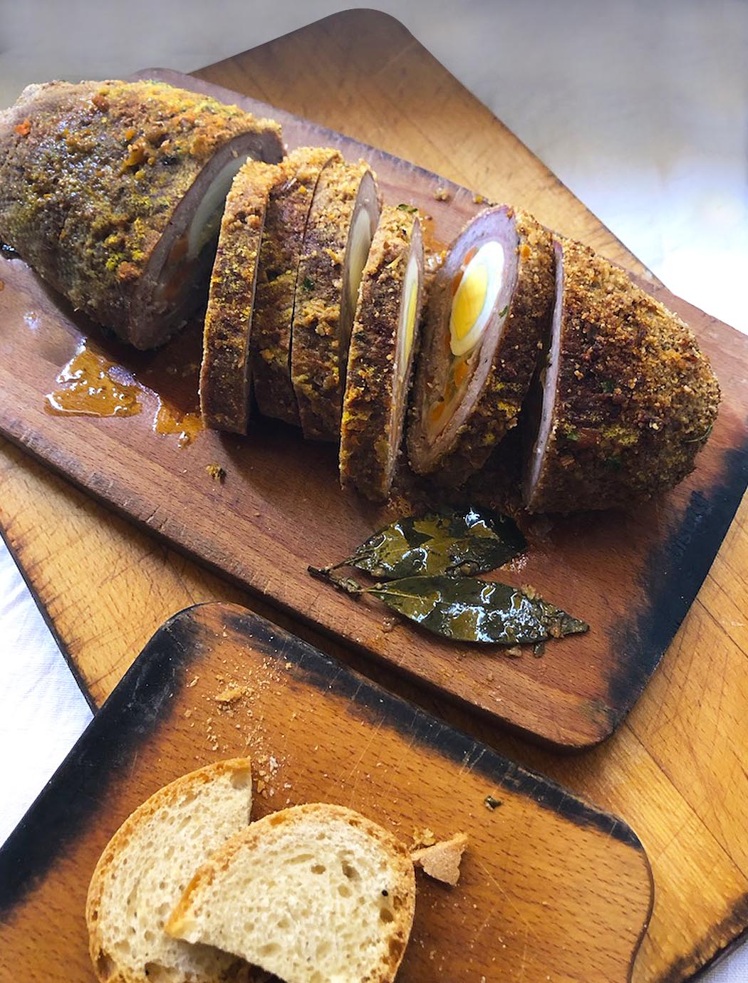 sliced Italian meatloaf on a chopboard with bread