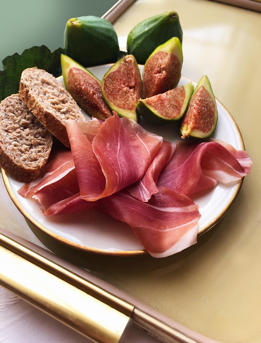 a dish with slices of bread, of prosciutto and a fig