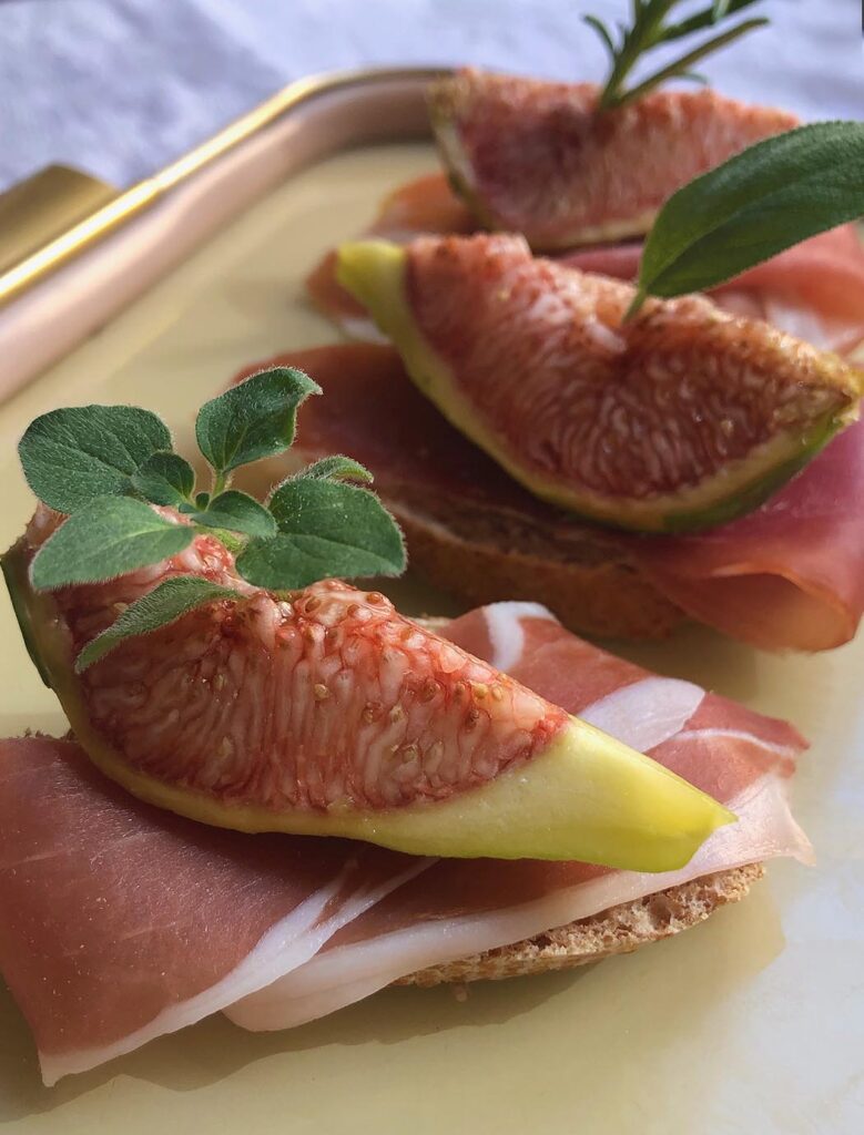 a snack made with a slice of bread covered by prosciutto and figs