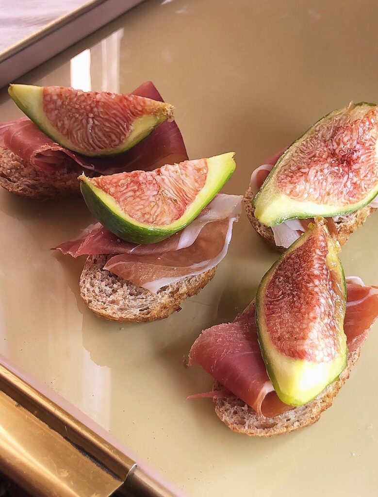 snack of bread, prosciutto and figs on a tray