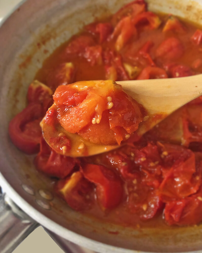 Tasting tomato sauce with a wood spoon