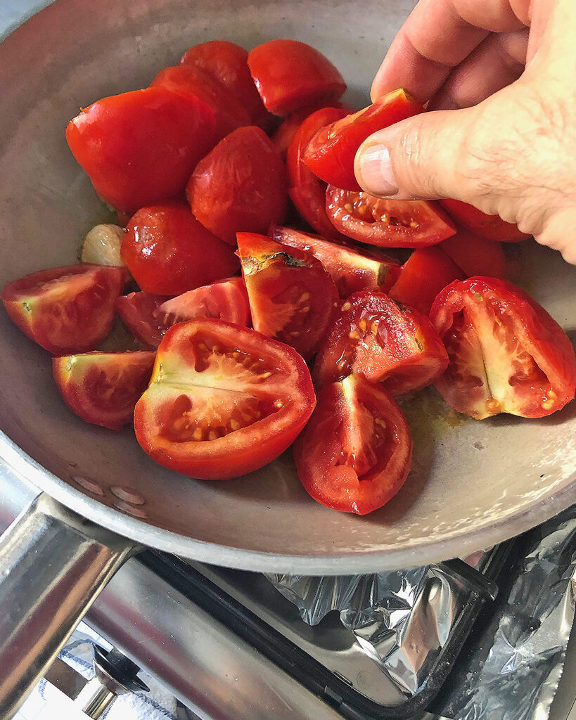 Putting pieces of tomatoes into a pan