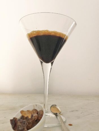 shaken coffee in a cocktail glass with raw sugar crystals