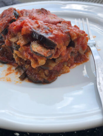 eggplant parmesan served on a white elgant dish with a fork