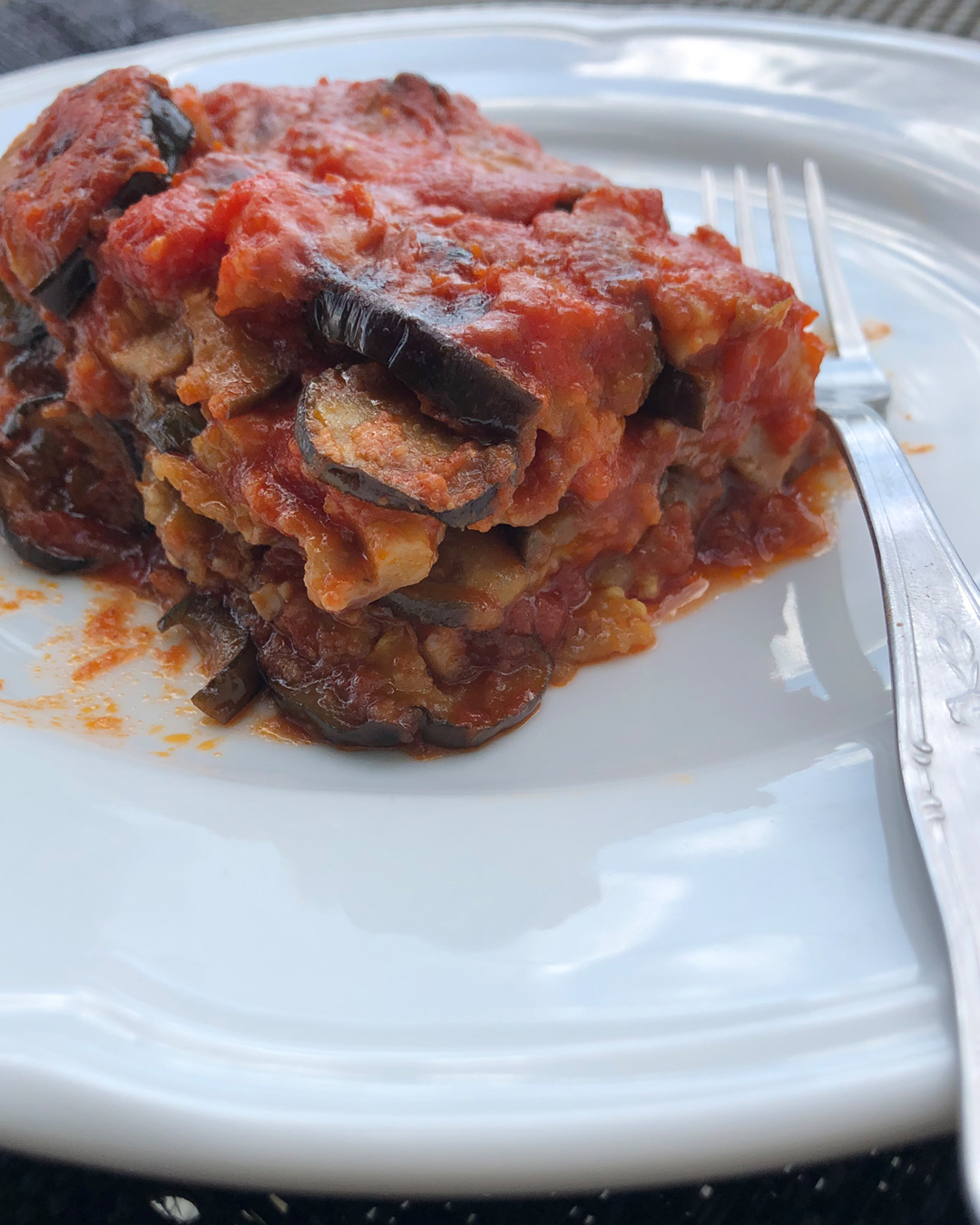 eggplant parmesan served on a white elgant dish with a fork