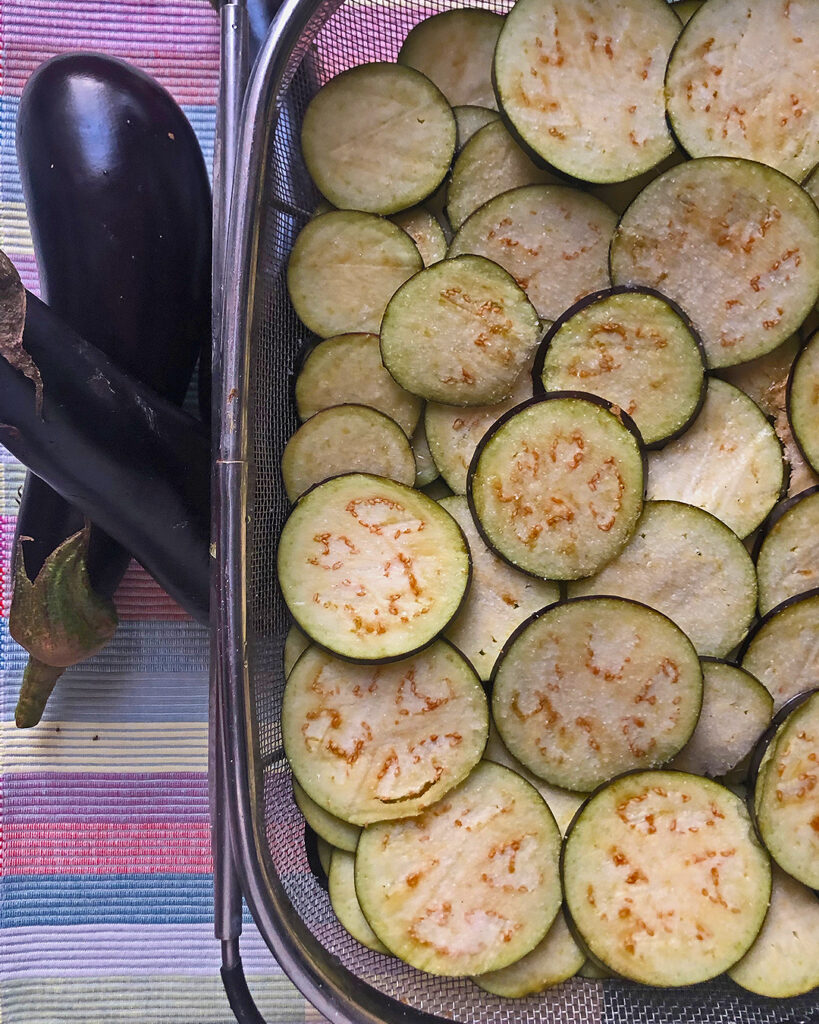 eggplant sliced in a coliender to drain the vegetable liquid