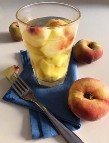 a fork, a glass full of wine and peach cubes