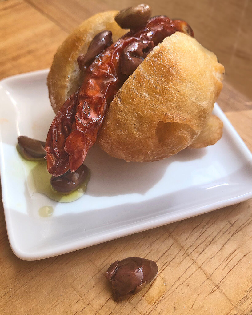 fried pizza with dried tomatoes and olives