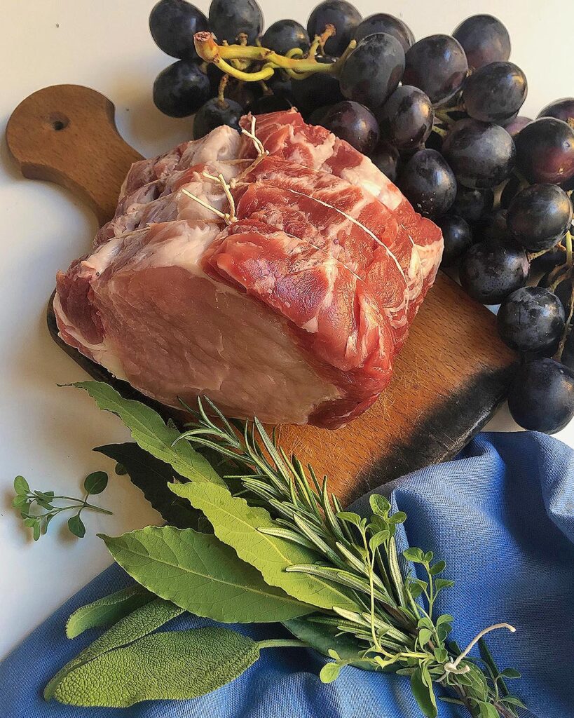 a piece of pork, grapes and fresh aromatic herbs