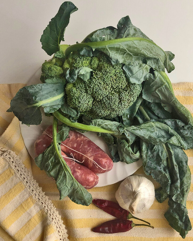 broccoli and sausage on a chop board ready to be cutted