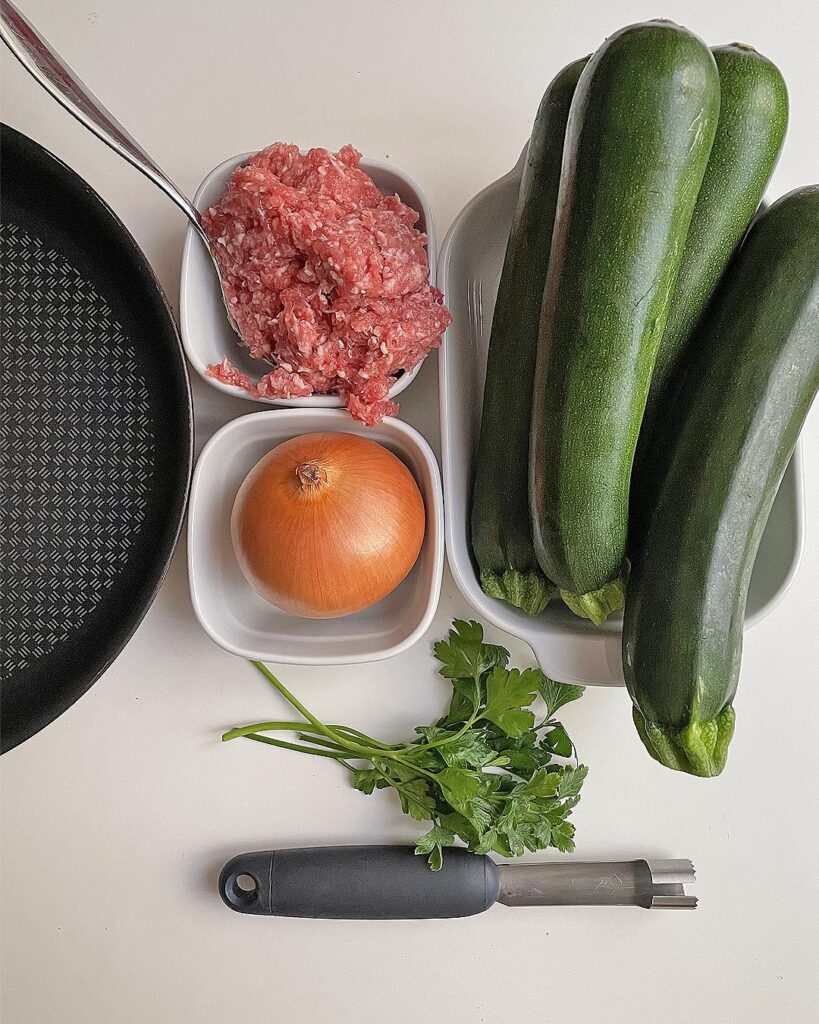 the ingredients for stuffed zucchini: zucchini, minced pork, onion, parsley