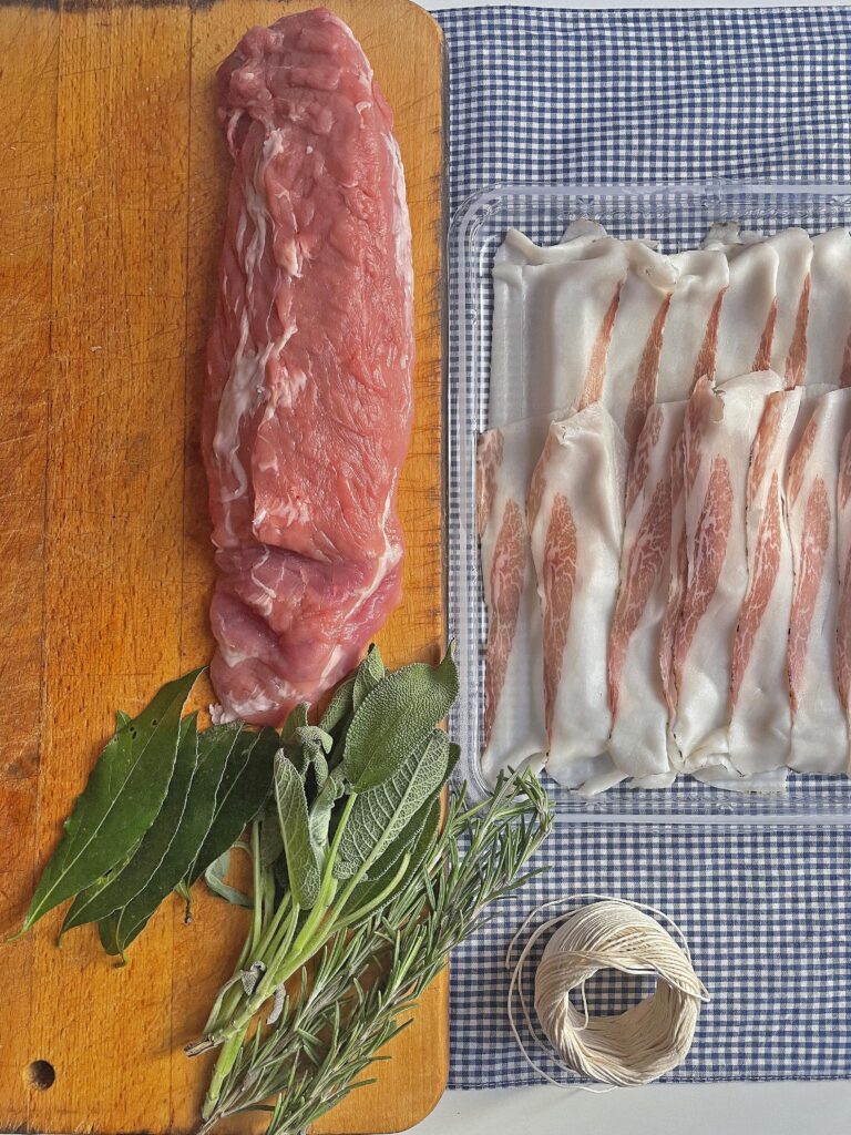 raw pork fillet ready to be cooked in a chop board with pancetta and aromatic herbs